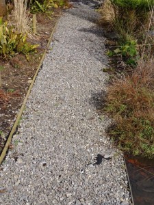 Stone mulch pathway in garden weed membrane blanket fabric